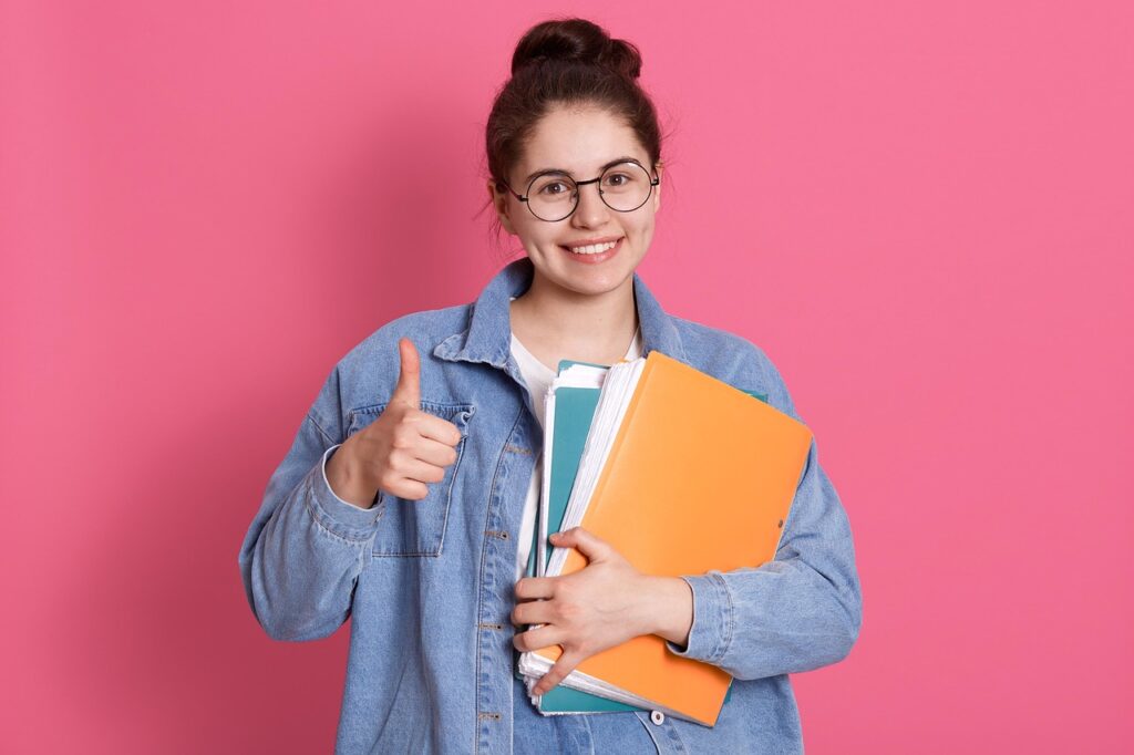 schoolgirl, student, college, document, books, thumbs up, success, casual attire, teenage, lifestyle, learn, adult, cute, documentation, paperwork, shirt, cheerful, academic, studying, education, eyeglass, portrait